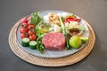 The uncookedÃÂ ingredients prepared for making yum steak, spicy Thai salad style, are arranged and placed on a local tray set